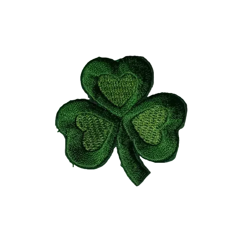 A green embroidered shamrock patch with stitched leaf details, shown on a plain light gray background.
